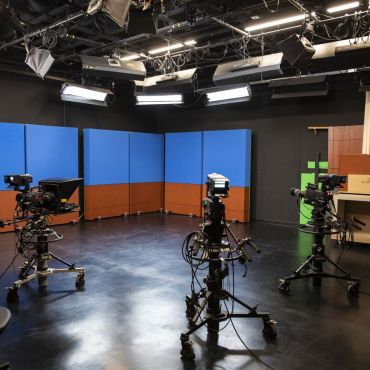 30’ X 30’ production studio is designed for flexibility and ease of use. Equipped with pre-lit,180-degree infinity green screen, numerous virtual sets, a customizable physical set with key-able windows, several news desks, black cyclorama as well as white, red and blue curtains.