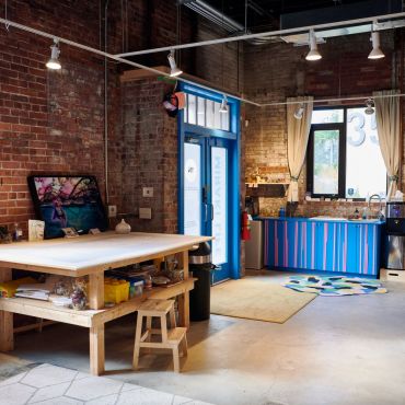 Craft table including art supplies, and kitchenette equipped with a complimentary snack bar and espresso machine.